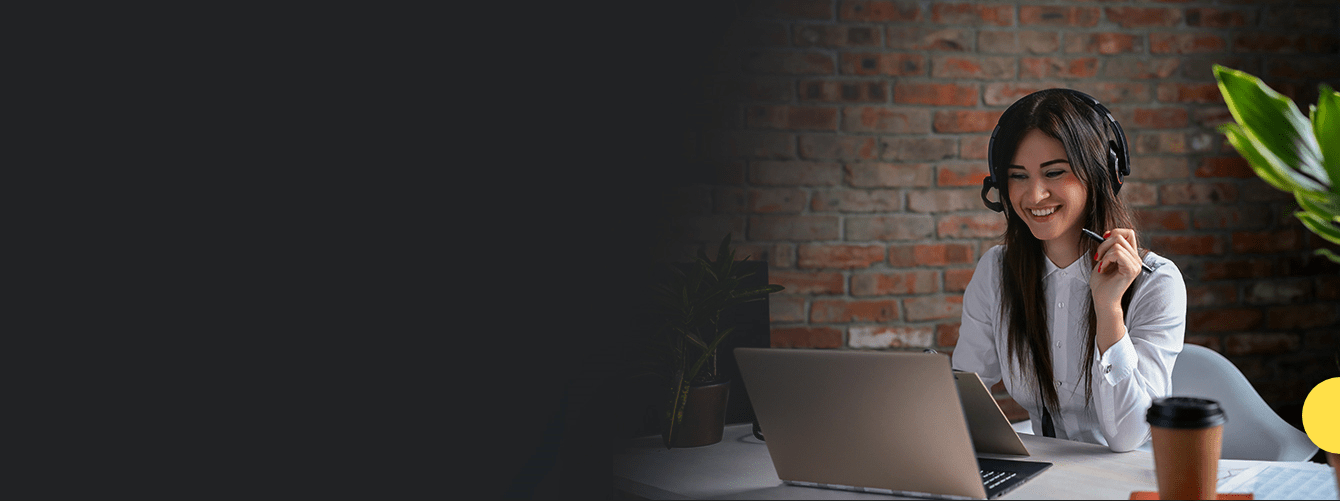 woman sitting at desk with headphones on looking at a laptop