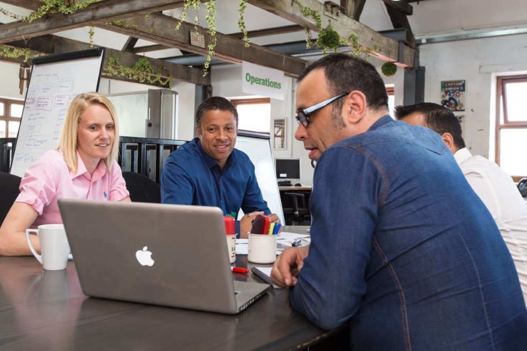 people sitting around a table looking at a laptop